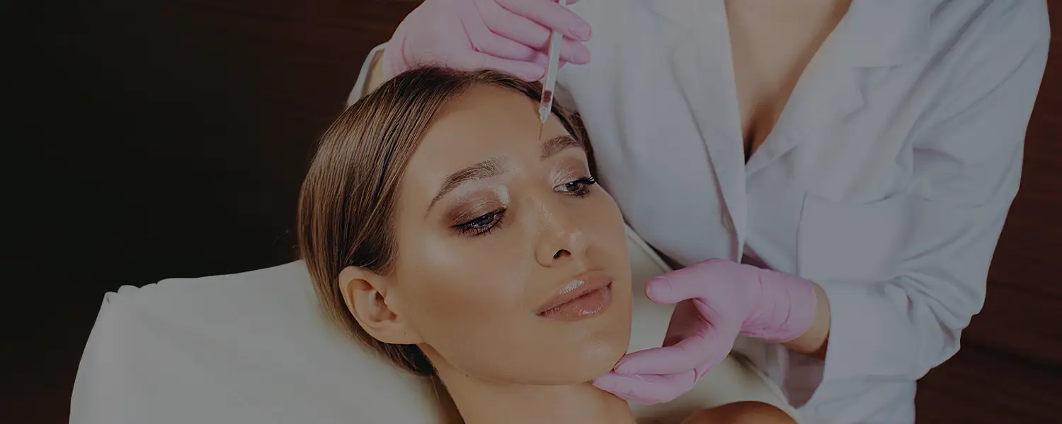 A woman gets a forehead botulinum injection from a professional in a clinical or spa setting.