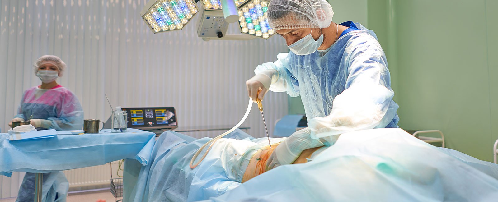 Surgeon performs liposuction on patient under bright lights
