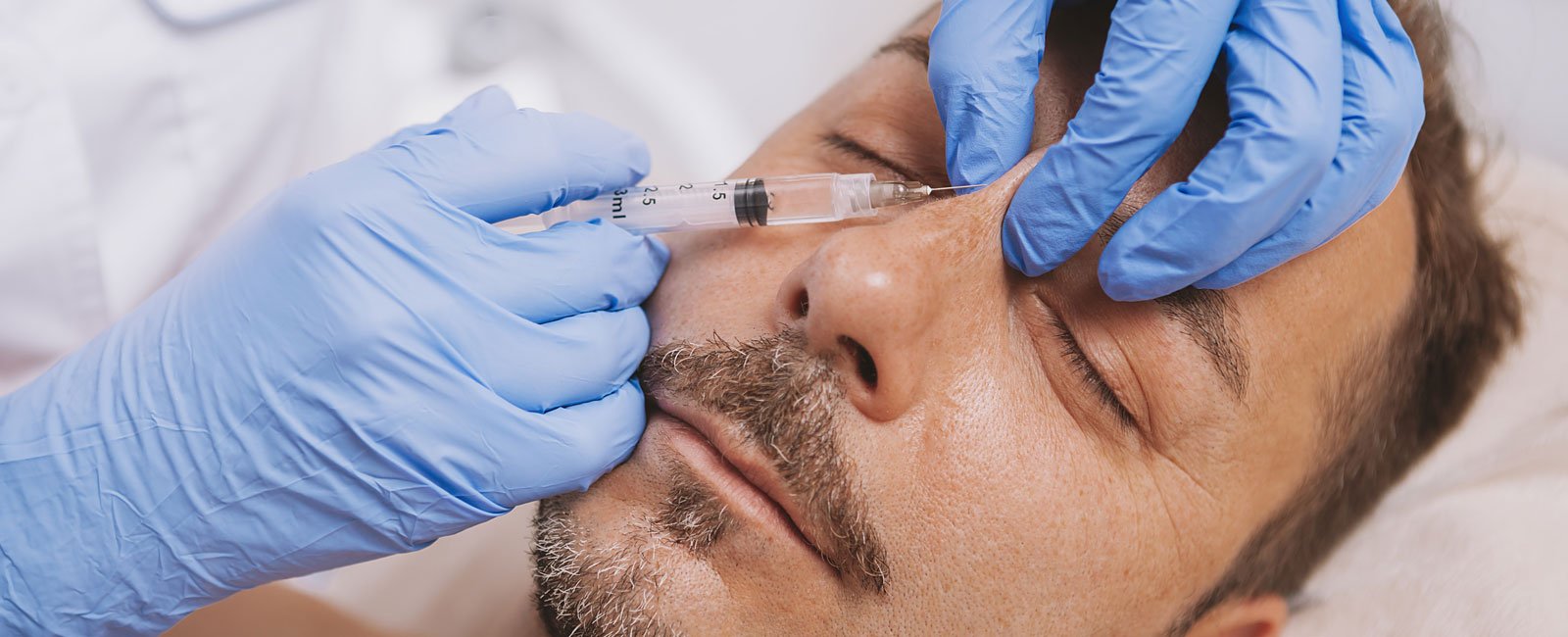 A professional injects a substance into a relaxed person's face during a non-surgical facelift.