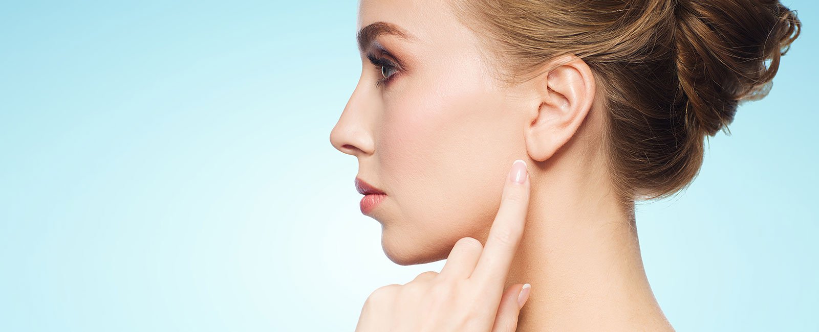 Woman with styled hair touching ear against light blue background.