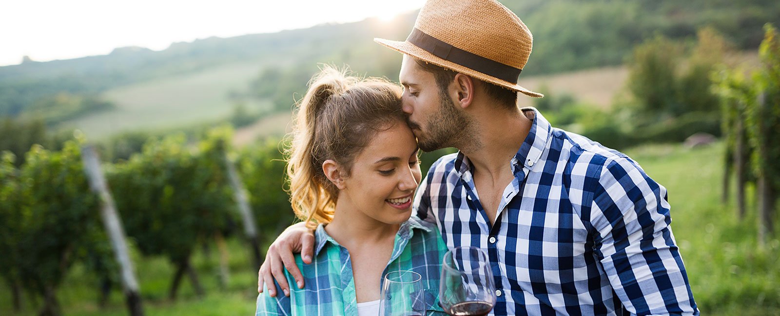 A couple in a vineyard: man kisses woman's forehead