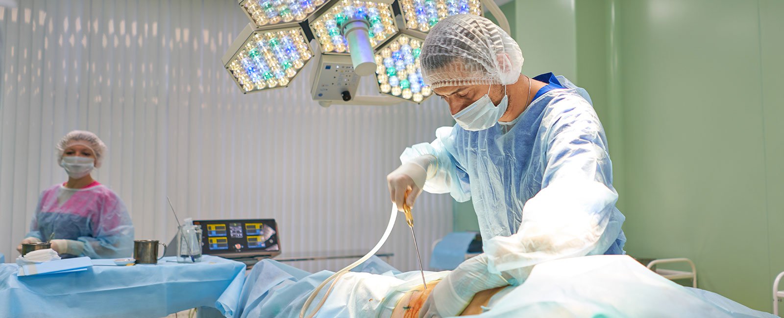 A plastic surgeon operates under surgical lights